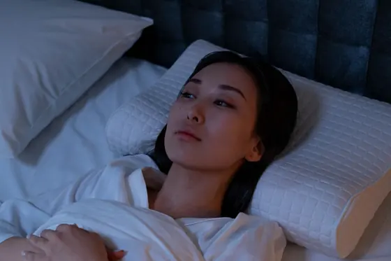 Mulher deitada na cama, acordada no meio da noite